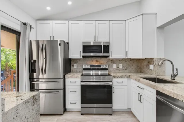 a kitchen with stainless steel appliances white cabinets and a stove top oven