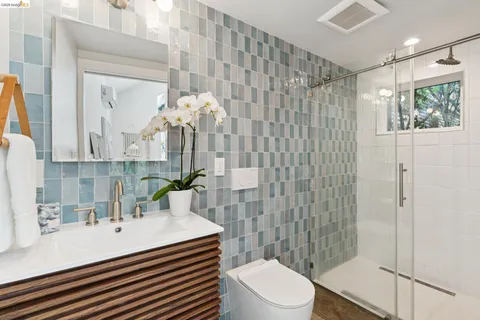 a bathroom with a sink a toilet a mirror and shower