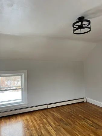 a view of empty room with wooden floor and window