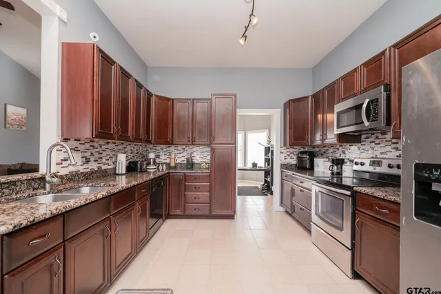 a kitchen with stainless steel appliances granite countertop wooden cabinets a stove top oven a sink and dishwasher