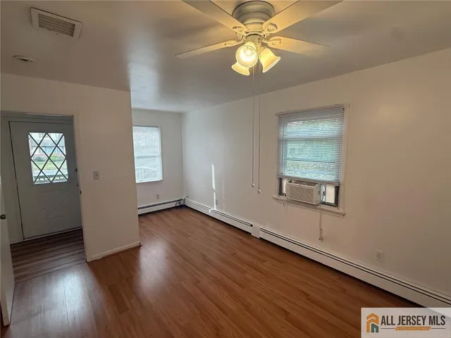 an empty room with wooden floor chandelier fan and windows