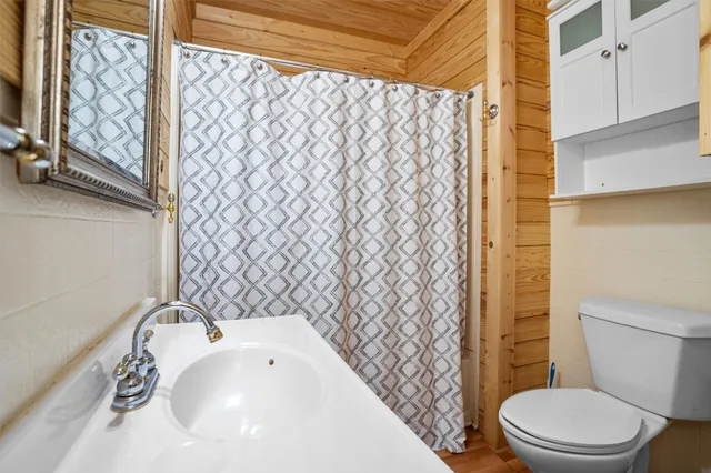 a white toilet sitting next to a white sink and a shower curtain