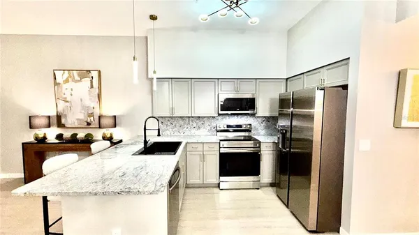 a kitchen with kitchen island granite countertop a stove a sink and a refrigerator