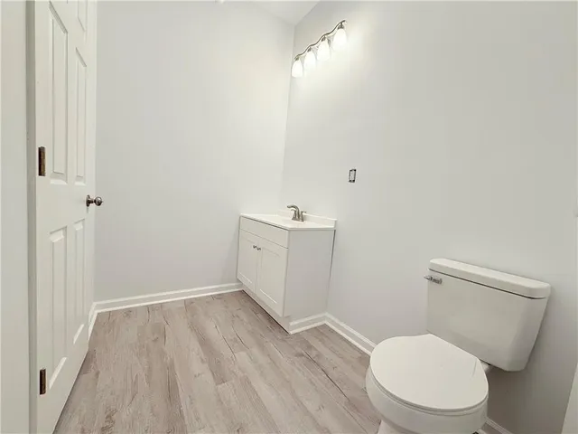 a bathroom with a toilet a sink and wooden floor
