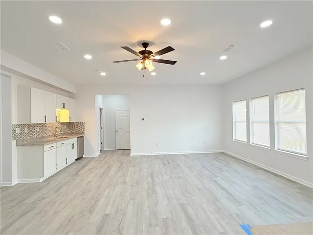 an empty room with chandelier fan and windows