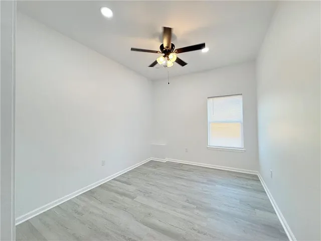 an empty room with a window and a ceiling fan