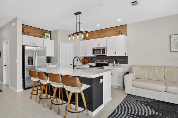 a kitchen with stainless steel appliances granite countertop a stove top oven a sink dishwasher a dining table and chairs with wooden floor