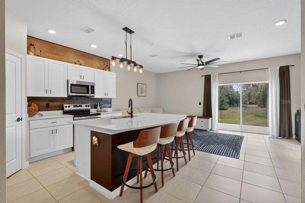 350 River Front Way Edgewater, FL 32141 - Photo 9 of 46 a kitchen with stainless steel appliances granite countertop a stove top oven a sink dishwasher a dining table and chairs with wooden floor