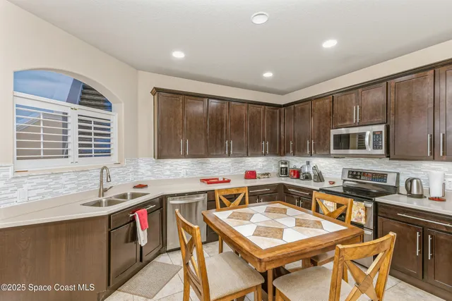 a kitchen with a stove a sink dishwasher a dining table and chairs with wooden floor