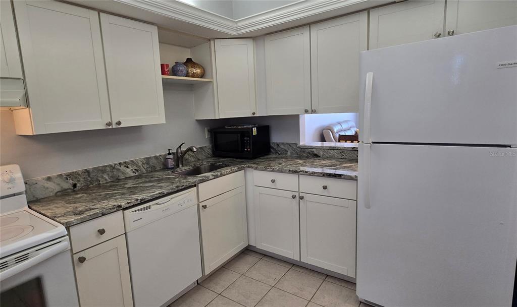 245 Center Road, Unit 104 Venice, FL 34285 - Photo 14 of 37 a kitchen with stainless steel appliances granite countertop a refrigerator sink and cabinets