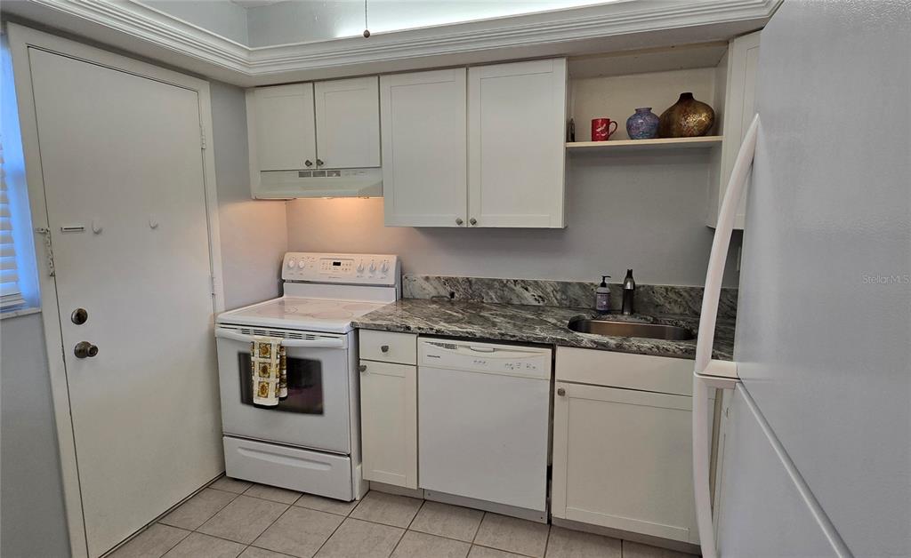 245 Center Road, Unit 104 Venice, FL 34285 - Photo 16 of 37 a kitchen with granite countertop white cabinets and white appliances