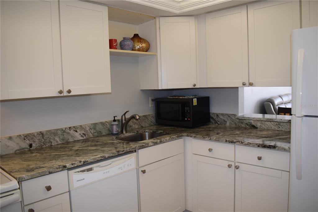 245 Center Road, Unit 104 Venice, FL 34285 - Photo 19 of 37 a kitchen with granite countertop white cabinets and a sink
