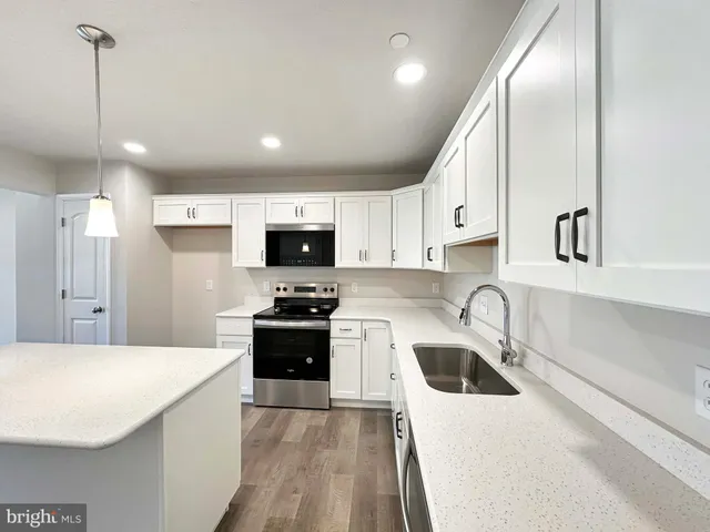 a hall with kitchen island a stove a wooden floor and a window