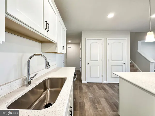 a kitchen with a sink and a stove top oven with wooden floor
