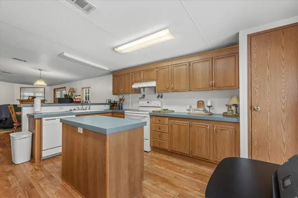 a kitchen with kitchen island granite countertop a sink cabinets and stainless steel appliances