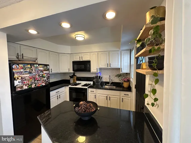 a kitchen with stainless steel appliances kitchen island granite countertop a stove refrigerator and microwave