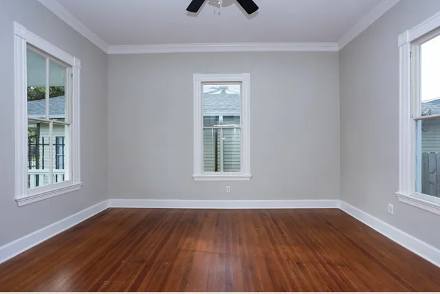 a view of an empty room with wooden floor and a window