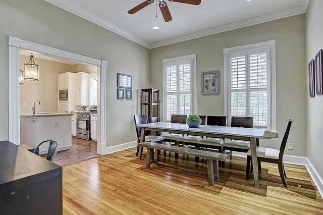 a dining hall with stainless steel appliances granite countertop a stove a sink a dining table and chairs with wooden floor