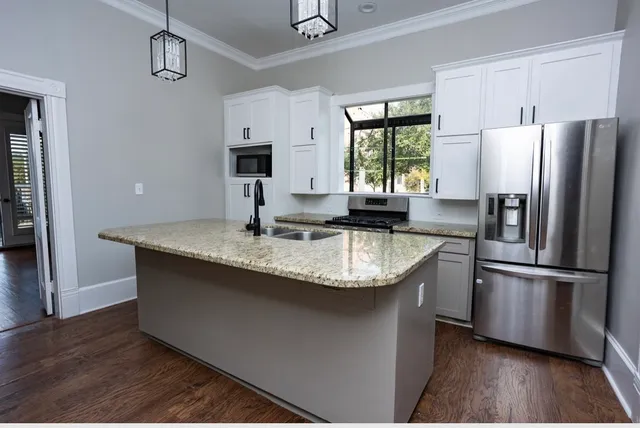 a kitchen with granite countertop stainless steel appliances a sink window and refrigerator