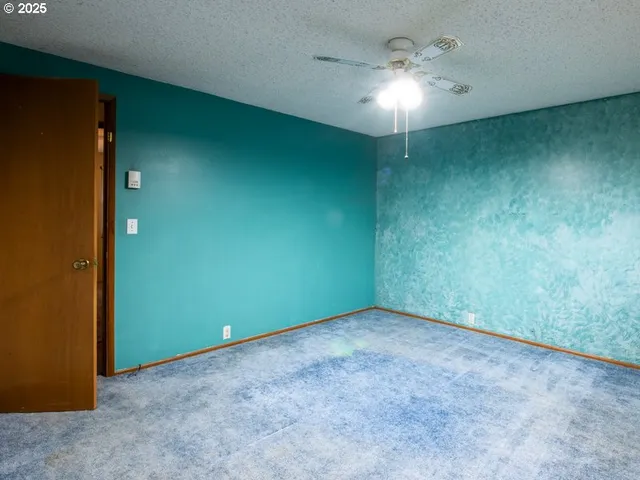 an empty room with a chandelier fan and windows