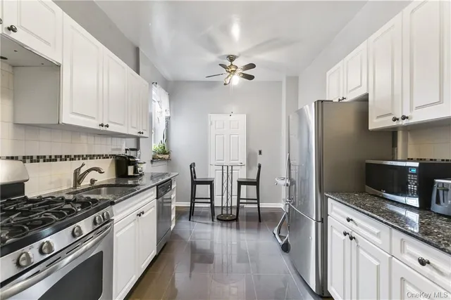 a kitchen with granite countertop a stove a sink a refrigerator and wooden cabinets