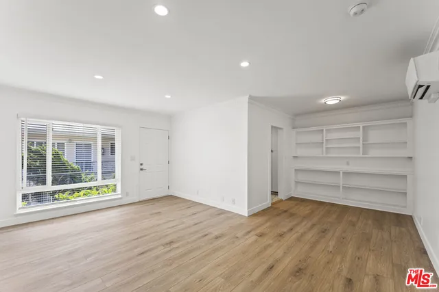 a view of an empty room with a window and wooden floor