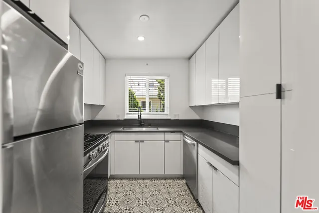 a kitchen with a sink a refrigerator and cabinets