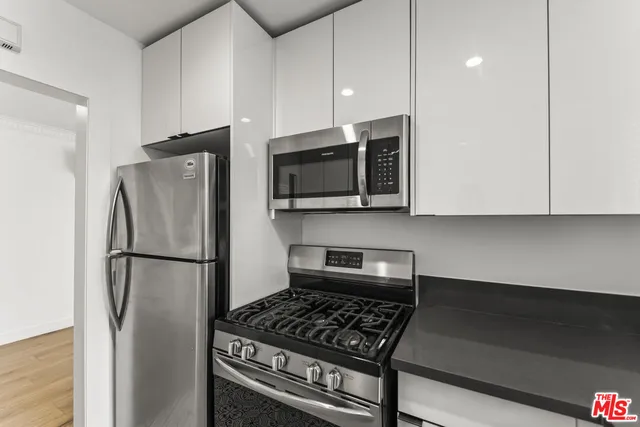 a kitchen with stainless steel appliances a refrigerator a stove top oven a sink and cabinets