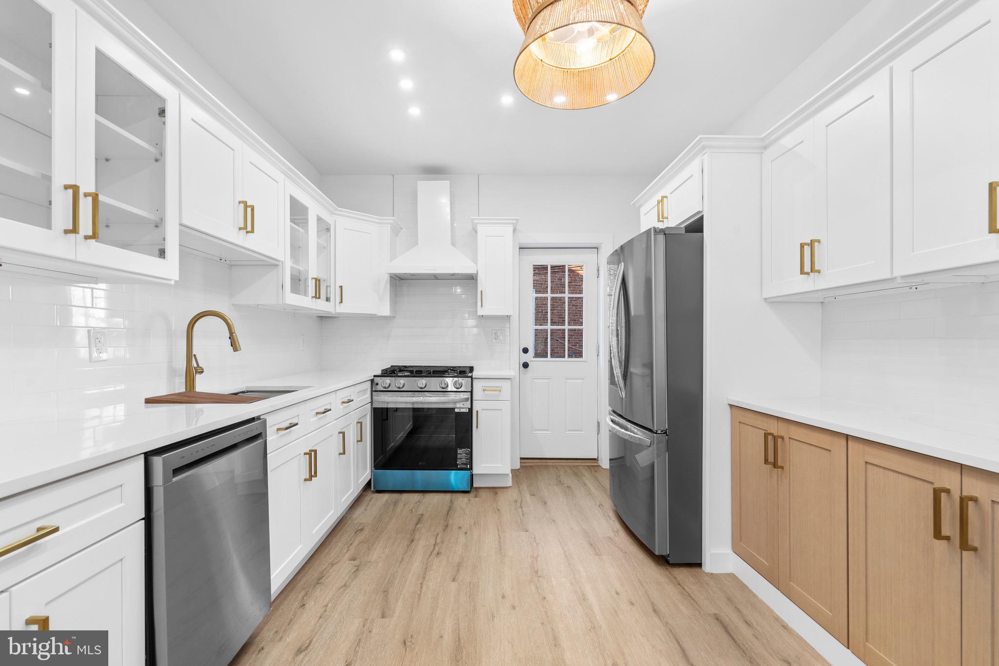 5541 Race Street Philadelphia, PA 19139 - Photo 8 of 37 a kitchen with stainless steel appliances granite countertop a refrigerator a sink dishwasher a stove and white countertops with wooden floor