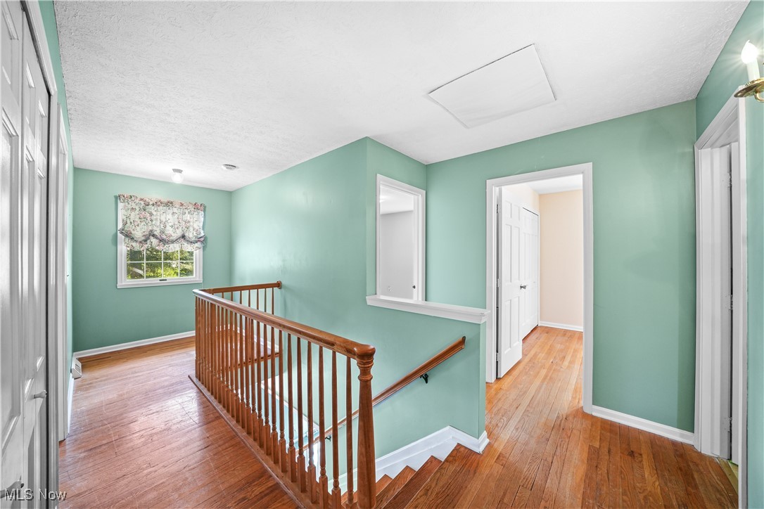 3325 Frantz Road Medina, OH 44256 - Photo 15 of 40 Hall with baseboards, an upstairs landing, hardwood / wood-style flooring, and attic access