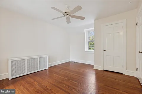 an empty room with wooden floor ceiling fan and windows