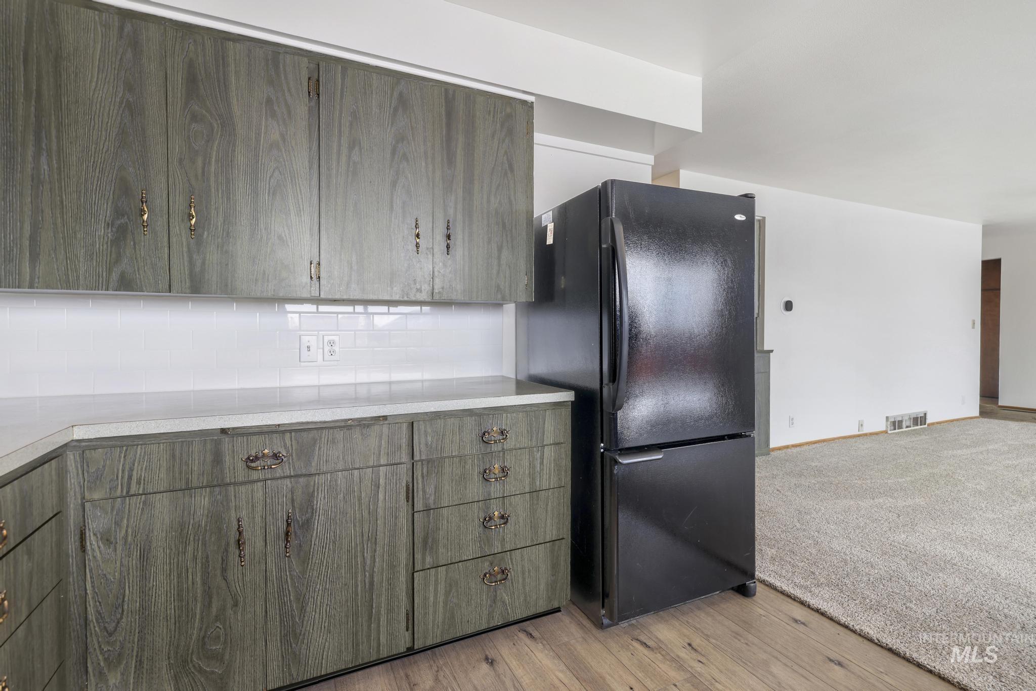 409 Clear Lakes Road Buhl, ID 83316 - Photo 10 of 43 Kitchen featuring freestanding refrigerator, light countertops, decorative backsplash, and light wood-style floors