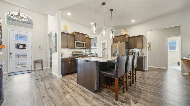 a kitchen with stainless steel appliances a dining table chairs refrigerator and microwave
