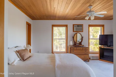 a bedroom with a large bed and a flat tv screen on dresser