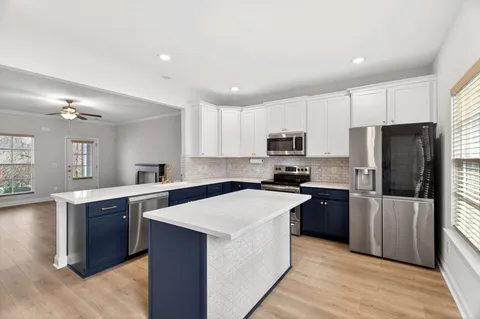 a kitchen with stainless steel appliances granite countertop a stove top oven a refrigerator a sink and dishwasher with wooden floor