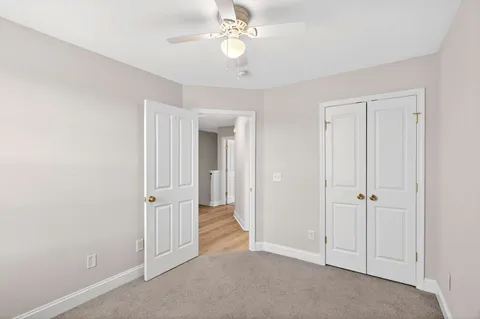 an empty room with closet and a ceiling fan