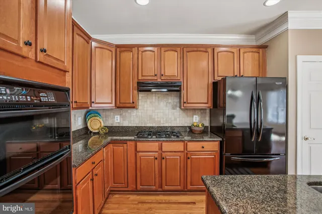 a kitchen with stainless steel appliances granite countertop a sink a stove and a wooden floors