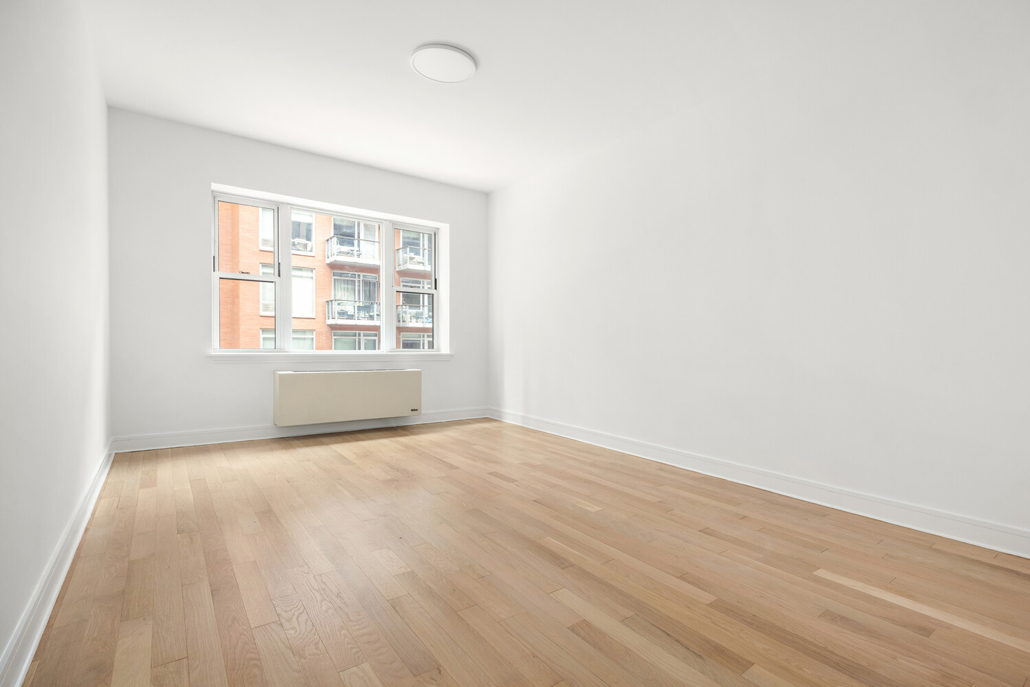 41-26 27th Street, Unit 3D Queens, NY 11101 - Photo 9 of 29 an empty room with wooden floor and windows