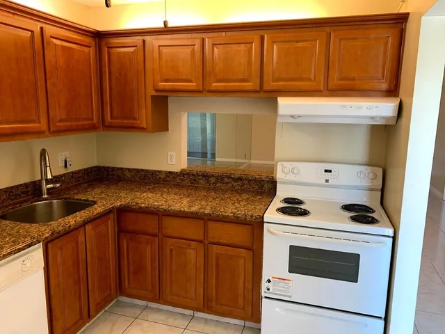 a kitchen with granite countertop stainless steel appliances a stove sink and cabinets
