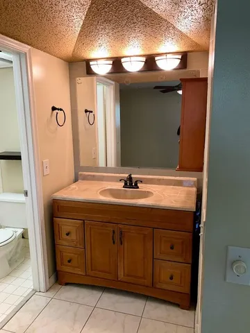 a bathroom with a granite countertop sink a toilet and a mirror