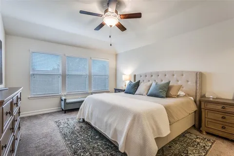 a bedroom with a large bed and a chandelier fan