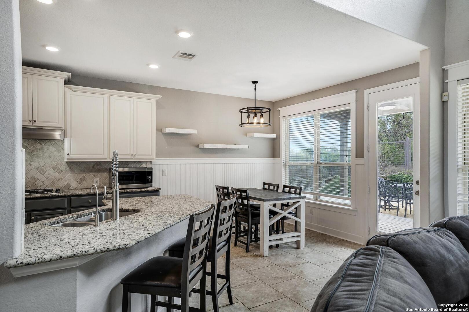 3754 Tumeric Cove Bulverde, TX 78163 - Photo 12 of 42 a kitchen with stainless steel appliances granite countertop table chairs sink and stove