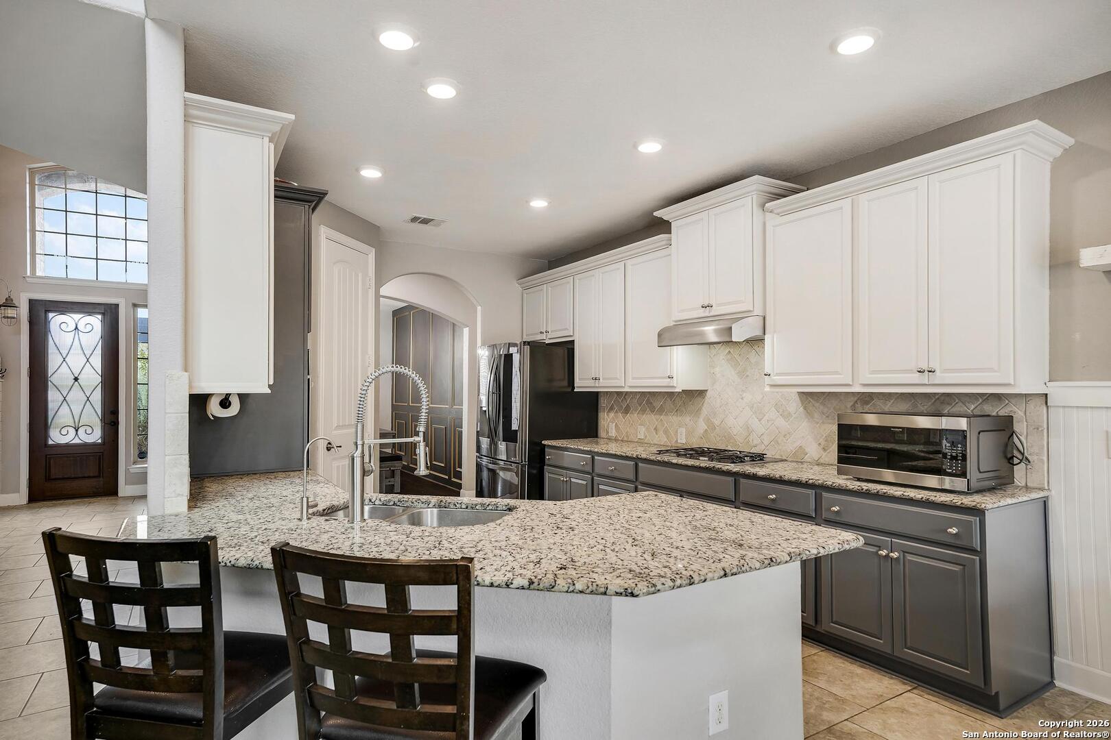 3754 Tumeric Cove Bulverde, TX 78163 - Photo 14 of 42 a kitchen with stainless steel appliances kitchen island granite countertop a stove a sink and a refrigerator