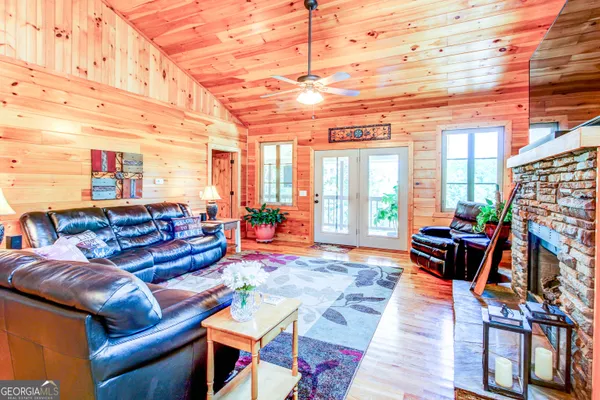 a living room with furniture a flat screen tv and a floor to ceiling window