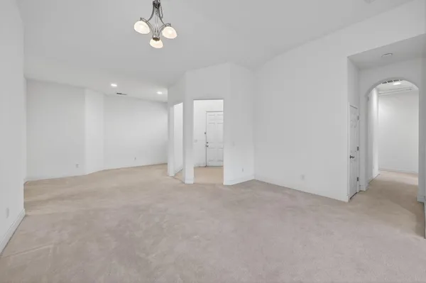an empty room with chandelier fan and windows