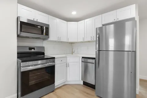 a kitchen with stainless steel appliances white cabinets white stove a microwave and a refrigerator