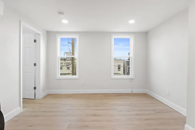 an empty room with wooden floor and windows