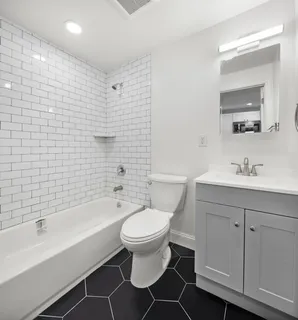 a bathroom with a bathtub shower sink mirror and toilet