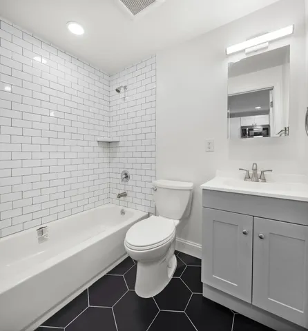 a bathroom with a bathtub shower sink mirror and toilet