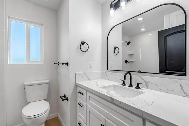 a bathroom with a granite countertop sink mirror vanity and toilet